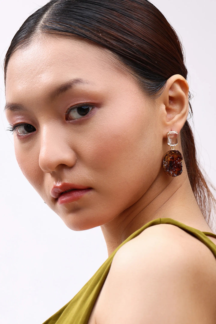 Model wearing Min & Lith Amber Fragment Drop Earrings, showcasing clear rectangular studs and richly textured amber-brown drops.