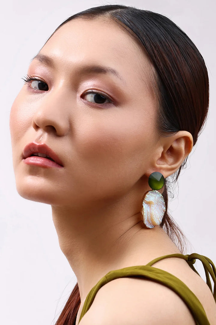 Model wearing Min & Lith Iridescent Ore Drop Earrings, featuring olive-green faceted studs and luminous peach-toned drops with an iridescent finish.