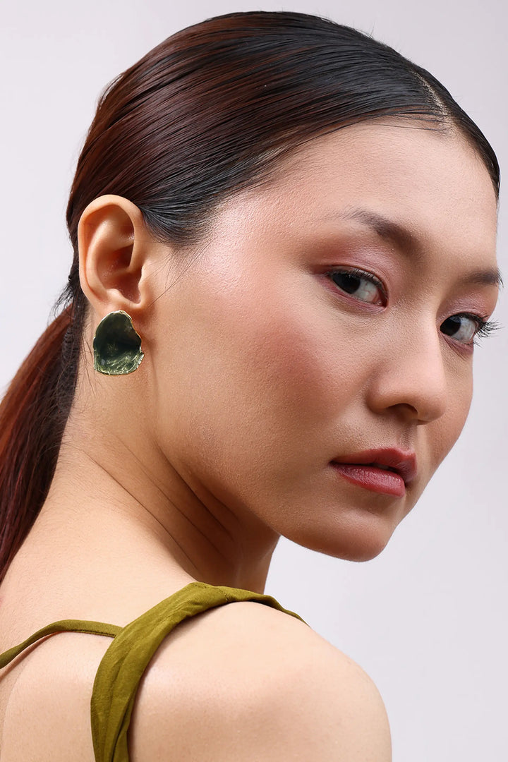 Model wearing Min & Lith Verdant Stud Earrings, showcasing their deep olive-green colour, organic shape and gold-toned edging.